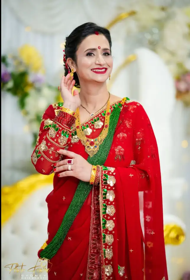 Bride in a red saree with statement gold jewellery, outdoors